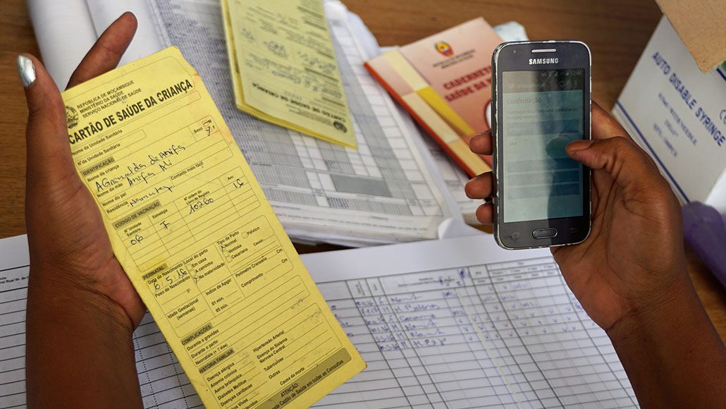 A female health worker uses a mobile app to record vaccination data in Mozambique