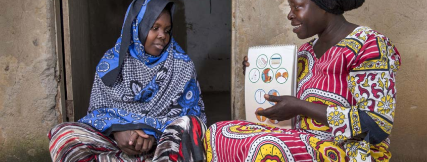 Female community health worker talks to a woman during a home visit in Uganda