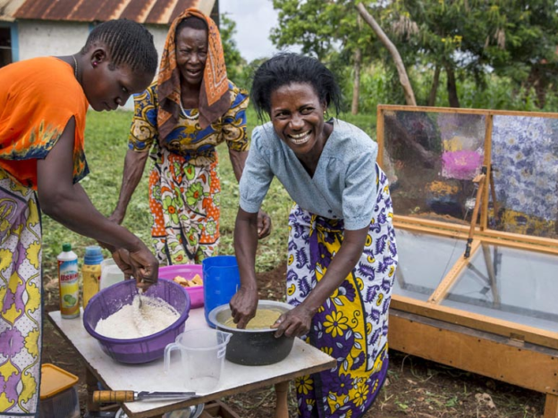 Three women preparing to bake cakes with a solar oven in Mombasa, Kenya