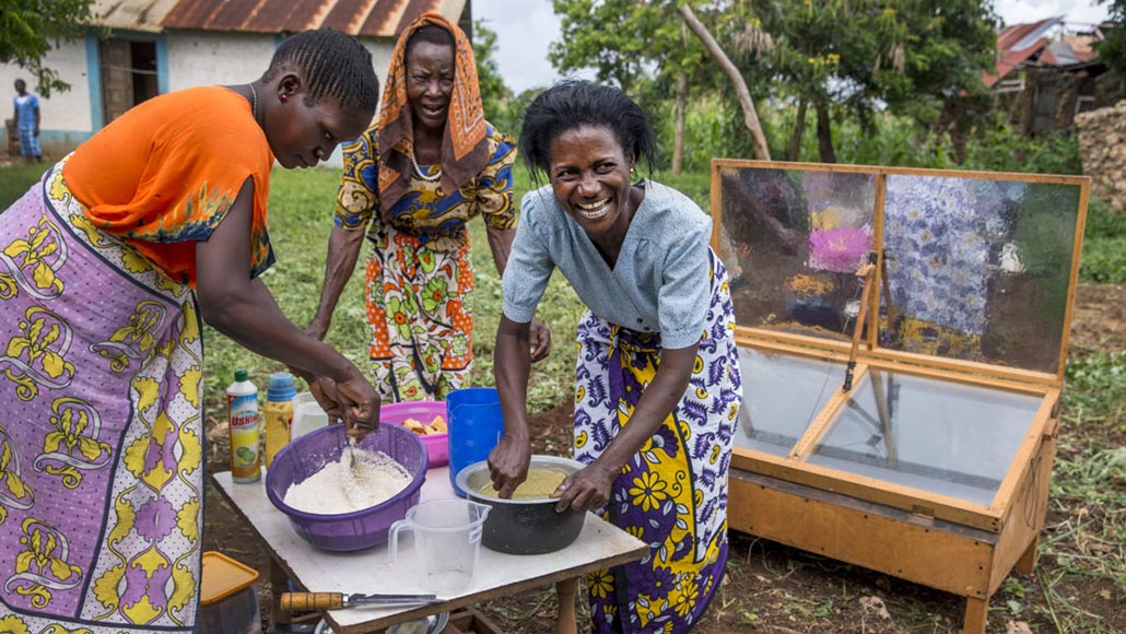Three women preparing to bake cakes with a solar oven in Mombasa, Kenya