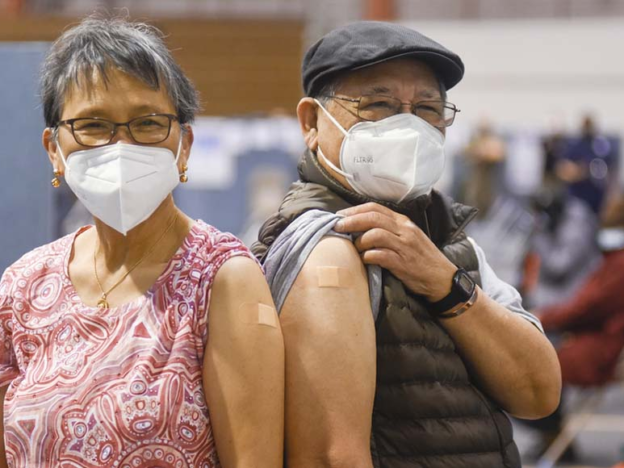 Two older adults with surgical masks and bandages after getting vaccinated in New York City